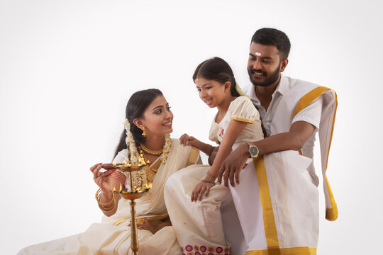south indian woman lighting lamp with a diya on onam