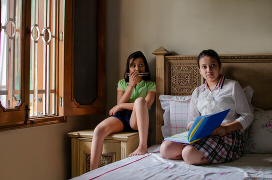girl playing mouthorgan and her sister is holding a file