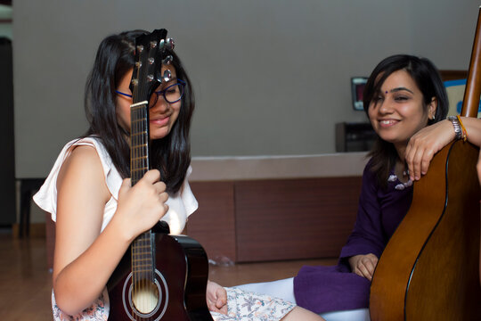 Young girl tired of practicing guitar with her mother 