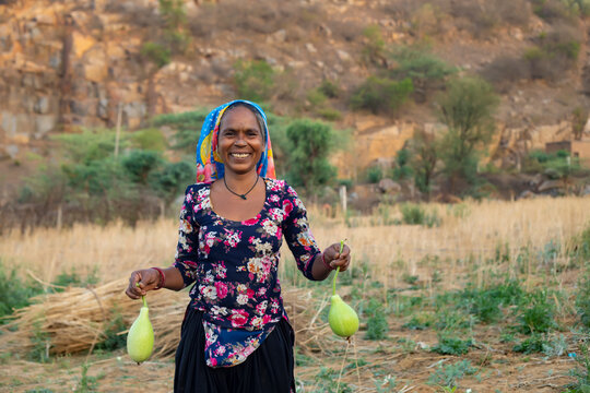 woman holding bottle gourd and smiling,in the field 