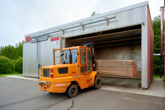 Forklift loading lumber into a drying kiln for wood processing