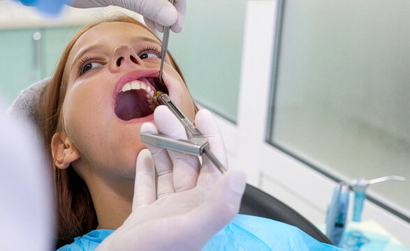Pediatric dentist giving local anesthesia injection to young girl patient