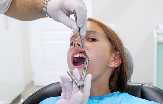 Pediatric dentist giving local anesthesia injection to young girl patient
