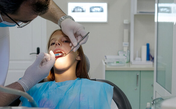 Pediatric dentist giving local anesthesia injection to young girl patient