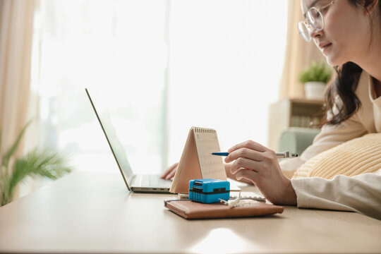 Close up female hands pointing pen on desk calendar searching vacation destination on laptop. Concept of travel planning, online travel agency booking, and personal itinerary planning with copy space.