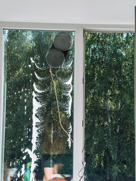 Robotic window cleaner washing glass window in home interior with trees outside.