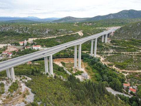 Vehicles moving on a high motorway bridge, aerial drone view. Traffic on a modern highway viaduct. Transportation on an elevated dual-carriageway.
