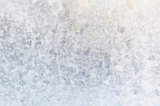 white winter background, frosty patterns on glass, abstract backdrop of ice and snow crystals in a blur