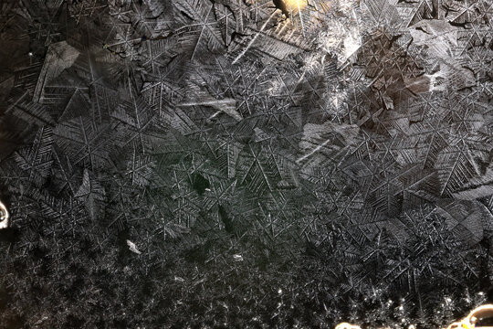 Ice crystals freezing on a black background, abstract winter photo surface