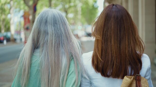 Two happy and stylish senior women friends enjoying their time together. Laughing and smiling heartily while standing against a brick wall. Showcasing a concept of lasting friendship and joy in aging
