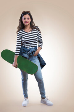 Young fashionable teenage girl standing with a skateboard in hand