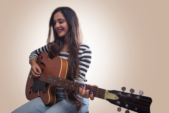 Smiling teenage girl playing guitar