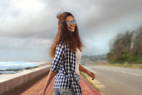 Woman wearing sunglasses looking back while walking on a road