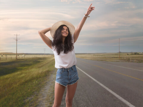 Woman standing on highway with raised hand to stop vehicle