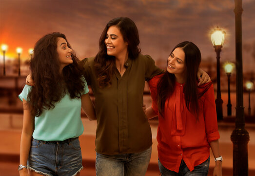 Three girl friends standing outdoors in evening