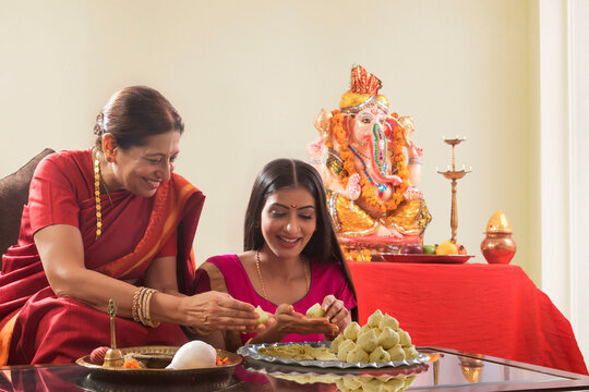 Mother in law teaching daughter in law how to make modaks on the occasion of Ganesh Chaturthi