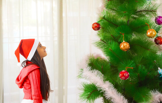 A little girl looking at a decorated Christmas tree