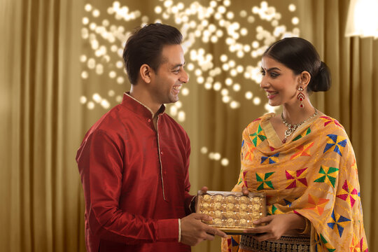 Happy Young Couple exchanging presents on diwali