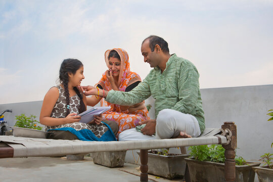 Indian mother and father helping daughters with homework