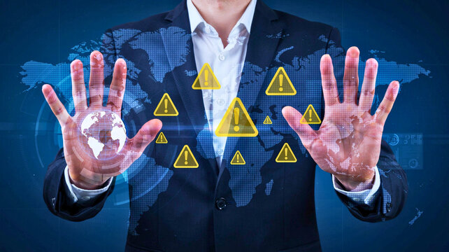 Businessman interacting with warning signs and digital world map hologram representing global cyber security and risk management