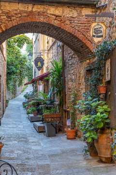 Old town street with archway and charming restaurant in Massa Marittima