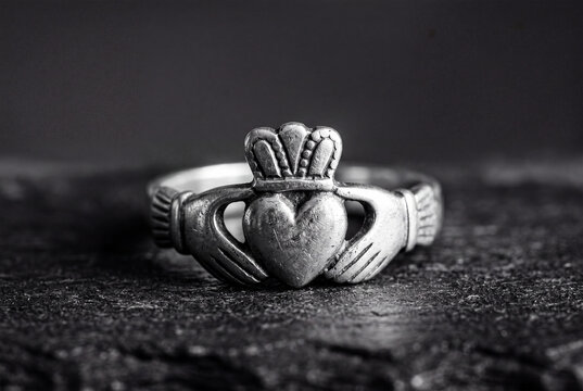 Antique Claddagh silver ring with crowned heart and hands on dark textured background close up