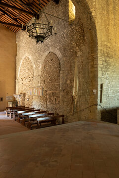 Old stone church interior with wooden pews in Cortona, Italy