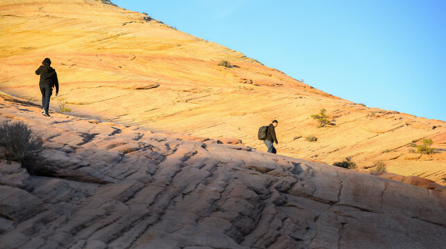 Hikers traversing the giant sandstone at sunset. Zion National Park. USA.