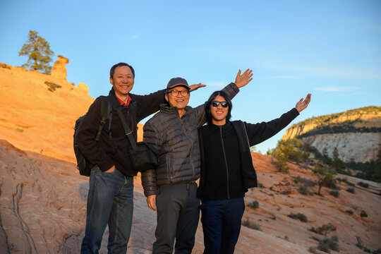 Hikers posing for a photo on the red rocks at sunset. Setting Sun casting a golden glow on the rocks. Zion National Park. Utah. USA.