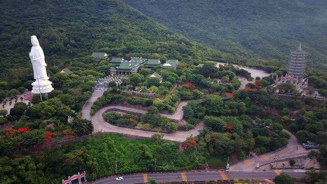 Smooth aerial orbit revealing the Lady Buddha statue, Linh Ung Pagoda and surrounding forest on Son Tra Peninsula in Da Nang, Vietnam.