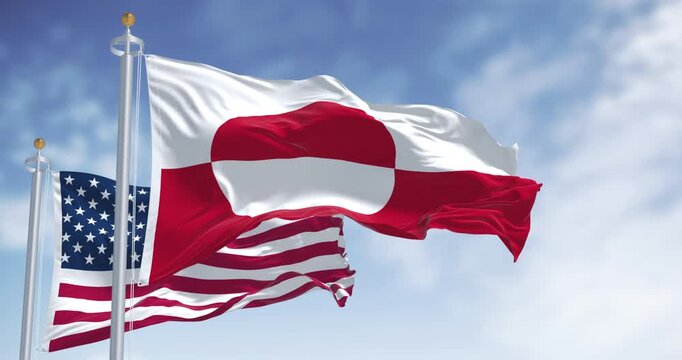 Flags of Greenland and the US waving in the wind on a clear day