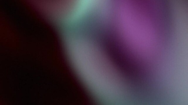 Abstract purple light leak shifting over dark textured background in vintage analog film style with gritty grain and cinematic lens flare distortion
