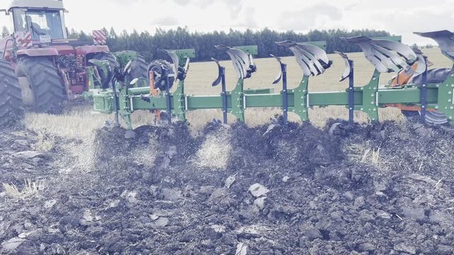 Modern tractor pulling a plow while working in the field. Realistic agricultural scene showing soil tillage, powerful machinery, and efficient land preparation.