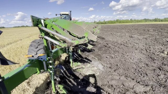 Modern tractor pulling a plow while working in the field. Realistic agricultural scene showing soil tillage, powerful machinery, and efficient land preparation.