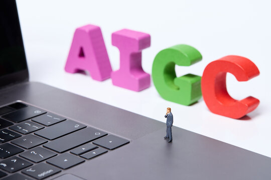 Miniature businessman on laptop keyboard with colorful AIGC letters