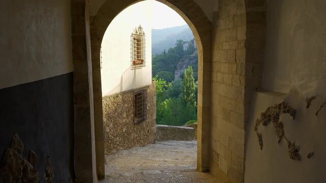 Stone arch passage opening toward the green Huecar valley in San Andres Cuenca Spain