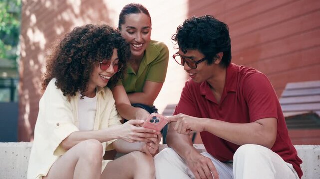 Video of three friends using smartphone while talking sitting on the street
