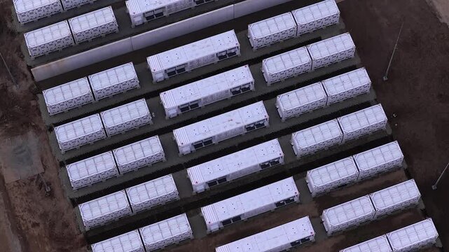 Modern battery energy storage system facility with containerized units for storing renewable power. High angle aerial view of the station