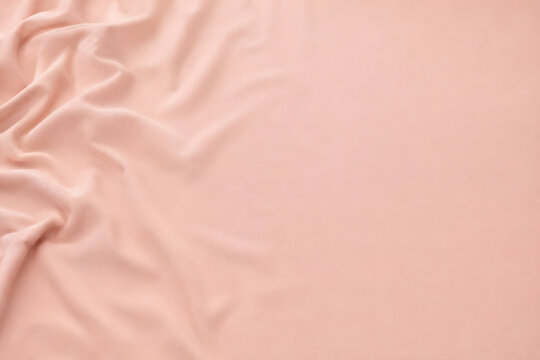 Top view flat lay of soft blush pink fabric with gentle folds and copy space.
