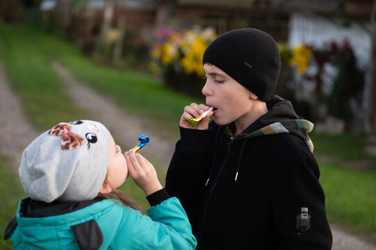 Joyful moments of two young friends sharing candy on a sunny day in an enchanting green landscape filled with blooming flowers