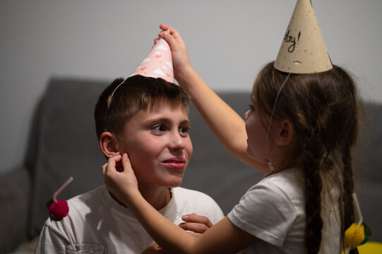 Joyful celebration with children wearing party hats in a cozy indoor setting during a festive birthday gathering