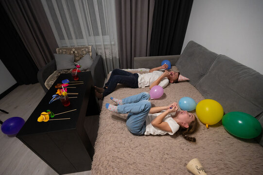 Children celebrating a joyful indoor birthday party with colorful balloons and playful decorations in a cozy living room setting during the evening hours