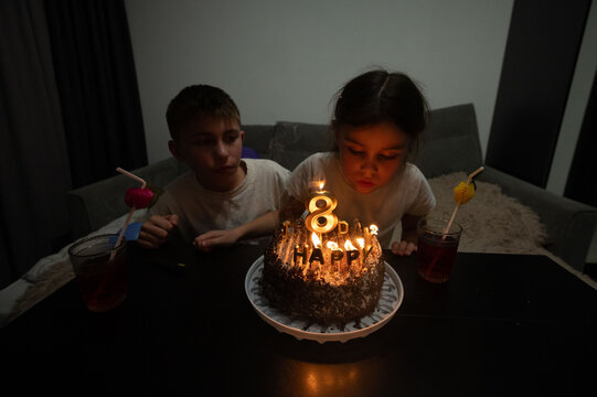 Birthday celebration with two children near a beautifully decorated cake at an evening gathering filled with laughter and joy