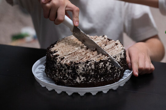 Delightful moments in a cozy kitchen as a child carefully slices a delicious chocolate cake with creamy layers, creating sweet memories during a special celebration