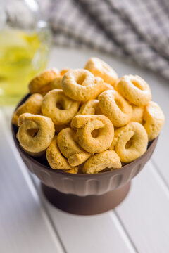 Bowl of Savory Taralli Ring Snacks on White Table with Olive Oil and Rustic Cloth
