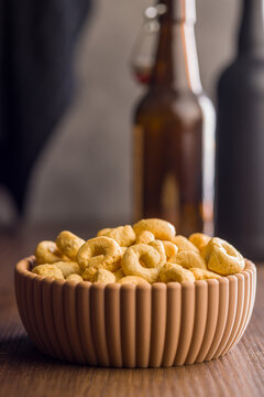 Bowl of Crunchy Taralli Snack Rings on Wooden Table With Bottles in Soft Background