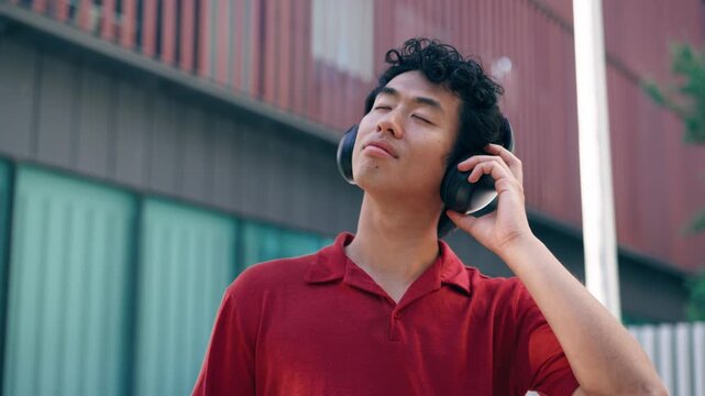 Video of cheerful man listening music with headphones on the street