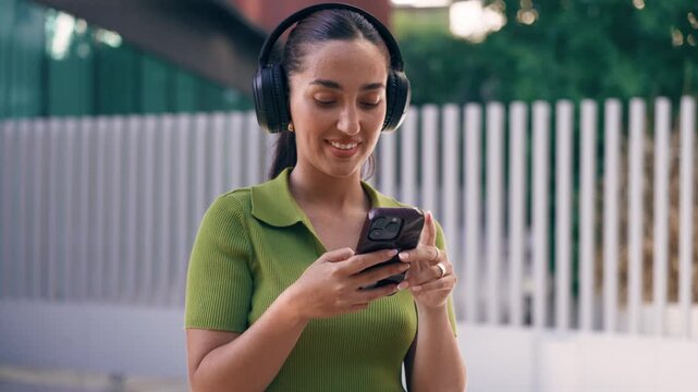 Video of beautiful woman using smartphone while listening music with headphones on the street