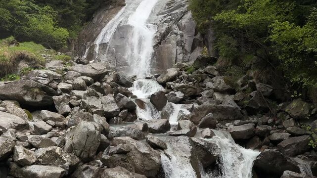 Cascata Amola waterfall in Val Nambrone, Italy, flows through a forested mountain landscape in the Dolomiti di Brenta