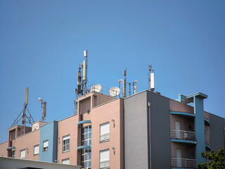 Fototapeta premium Tecnologia no topo de um edifício com algumas antenas 4G, 5G e repetidores de sinal contra um céu azul